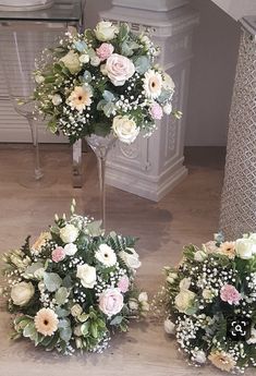 three vases filled with flowers on top of a wooden floor next to a stair case