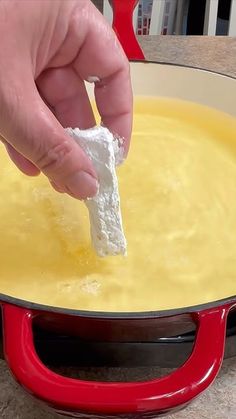 a person is dipping cheese into a pan