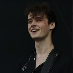 a young man smiling and wearing a black shirt