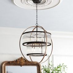 a chandelier hanging from the ceiling in a room with mirror and potted plant