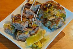 a white plate topped with meat and veggies on skewered toothpicks