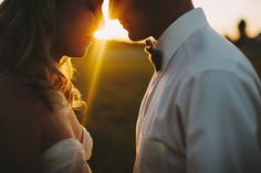 a bride and groom standing close to each other in front of the sun at their wedding