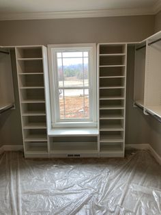 an empty room with some shelves and a window in the middle that is covered by plastic