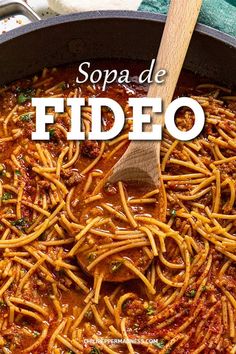 a pan filled with pasta and sauce on top of a table next to a wooden spoon