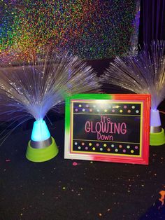 there are two colorful lights on top of each other in front of a sign that says the glowing down