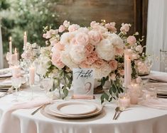 the table is set with white and pink flowers, candles, and napkins for an elegant centerpiece