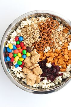 a metal bowl filled with cereal, pretzels, and other snacks to eat