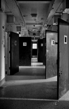 black and white photograph of an empty room with two doors leading to another room that has no one in it