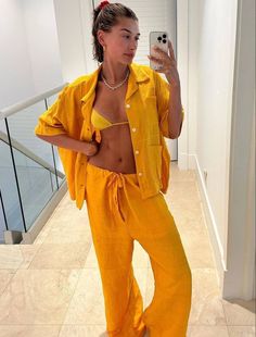 a woman taking a selfie with her cell phone in a yellow outfit on the stairs