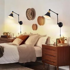 a bed room with a neatly made bed and three lamps on the wall above it