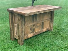 a wooden bench sitting on top of a lush green field next to a small tree