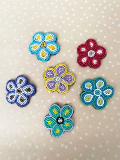 four different colored flowers on a white polka dot tablecloth, one is blue and the other is red