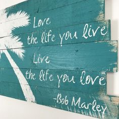 a wooden sign that says live the life you love with palm trees and words painted on it