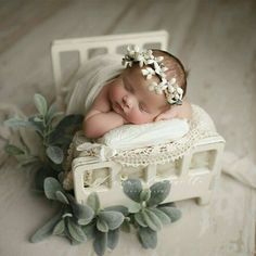 a newborn baby is sleeping on top of a white box with greenery around it