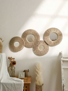 three circular mirrors hanging on the wall above a table and vase with flowers in it