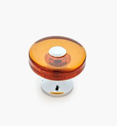 an orange and brown glass knob on a white surface