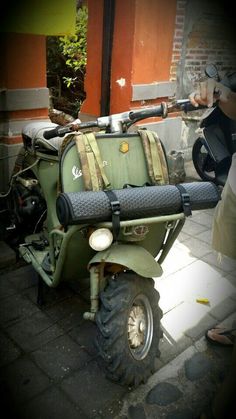 an old green scooter is parked on the sidewalk