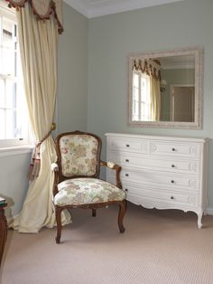 a bedroom with a chair, dresser and mirror