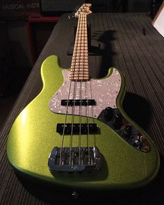 a green bass guitar sitting on top of a table