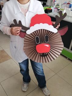 a young boy holding up a paper plate with reindeer decorations on it