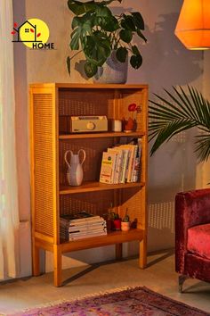 a living room with a red chair and a wooden book shelf next to a potted plant