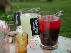 three different colored drinks sitting on top of a table next to each other in glasses