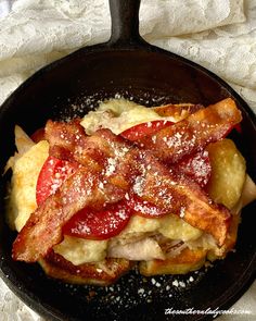 an iron skillet filled with bacon and cheese on top of a white table cloth