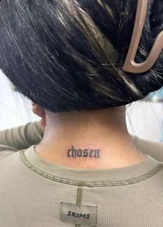 the back of a woman's neck has a cross tattooed on it