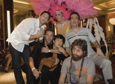 a group of people posing for a photo in front of a large pink feathered object