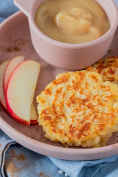 a plate with some food on it next to a bowl of sauce and an apple