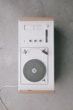 an old fashioned record player sitting on top of a white box with wires attached to it