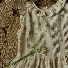 a white dress with flowers on it sitting next to some straws and other items