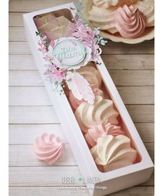 a box filled with pink and white frosted cupcakes