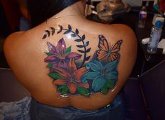 the back of a woman's shoulder with flowers and butterflies painted on her body