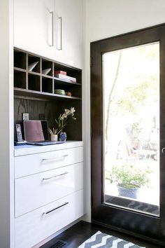 a black and white door is open to a room with shelves, drawers, and a rug on the floor