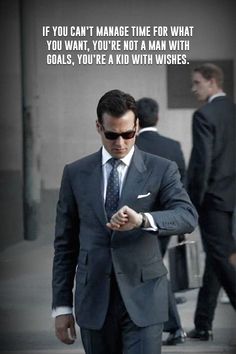 a man in a suit and sunglasses is looking at his cell phone while walking down the street