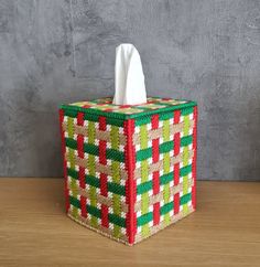 a tissue box made out of woven material with red, green and white squares on it