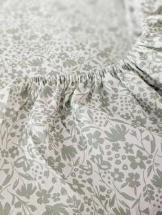 a close up view of the ruffles on a floral bedding with white and green flowers