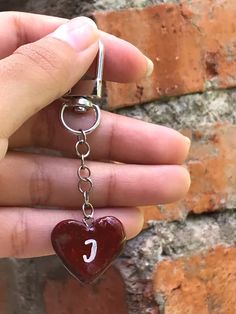 a person holding a heart shaped keychain with the letter c on it's side