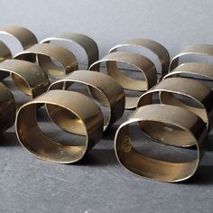 an assortment of brass rings sitting on top of a gray table next to each other