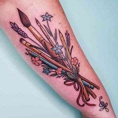 a woman's leg with an arrow and flowers tattoo on the left side of her arm