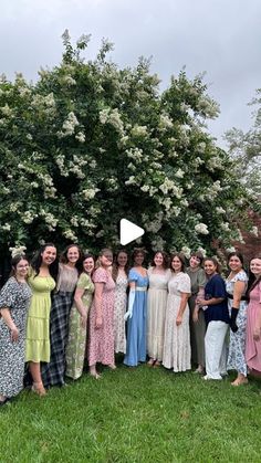 a group of women standing next to each other in front of a tree