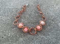 The Pink Nest Bracelet features polished agate stones in rich pink and cream hues with flecks of yellow and orange, wrapped in high-quality pure copper.  Flaunt this modern, art-deco-inspired look with a sophisticated feel to compliment your style and elevate any outfit. Give as a memorable unique gift to the favorite woman in your life: For Mother's Day, anniversary presents, Christmas gifts, birthday gifts, graduation and bachelorette parties. ## Sizing Total length is 7.5 inches. ## Materials Every item is 100% handmade and one-of-a-kind. The wire-wrapped raw copper jewelry is oxidized and polished to beautifully highlight details of the wirework. Finally, it's sealed with a protective clear coat to prevent tarnishing and allergic reactions. Since gemstones are unique, a slight variatio Handmade Copper Wire Jewelry With Round Beads, Handmade Rose Gold Bracelets With Round Beads, Handmade Rose Gold Bracelet With Round Beads, Handmade Adjustable Rose Gold Jewelry, Pink Hand Wrapped Round Beads Jewelry, Pink Hand Wrapped Round Bead Jewelry, Adjustable Handmade Rose Gold Jewelry, Hand Wrapped Pink Round Beads Jewelry, Hand Wrapped Pink Round Bead Jewelry