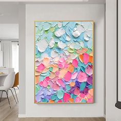 an abstract painting is hanging on the wall in a white room with wooden flooring