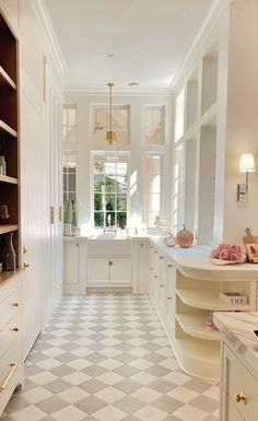 a white kitchen with checkered flooring and cabinets in the corner, next to a window