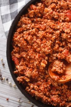 a skillet filled with meat and spices on top of a checkered table cloth