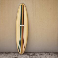 a surfboard leaning up against a wall with stripes on the bottom and bottom of it