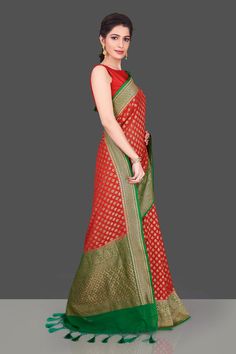 Look traditional on festive occasions in this red georgette Banarasi sari! The saree is adorned with antique zari small floral buta and has a contrasting green antique zari border and pallu. Shop online from Pure Elegance. Disclaimer: The shown stitched blouse on the model is for display purpose only. The saree comes with a matching blouse piece and finished with fall and piko. The actual product may vary slightly from the image. These are custom orders, hence expect slight variation in color, p Georgette Banarasi Saree, Muga Silk, Banarasi Sari, Green Antique, Fashion Journals, Banarasi Saree, Indian Sari, Traditional Fabric, Saree Online