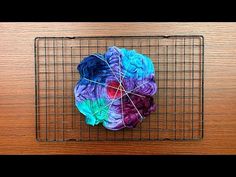 a piece of yarn sitting on top of a wire rack next to a wooden table