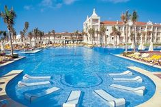 an outdoor swimming pool with chaise lounges and palm trees